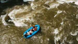 Un grupo sonriente en una balsa de rafting navegando por un rápido de clase III en el río Balsa con exuberante selva tropical y montañas al fondo.